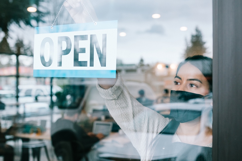 woman putting up open sign